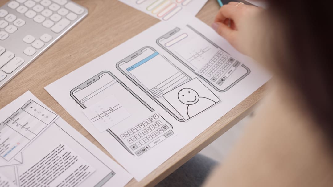 Designer sketching a homepage wireframe with a headline and call-to-action button at the top