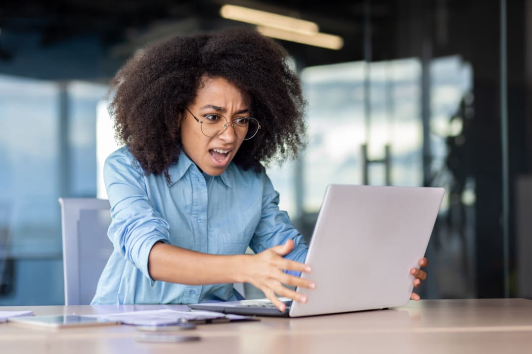 Frustrated person waiting at a laptop showing a loading spinner on a slow website