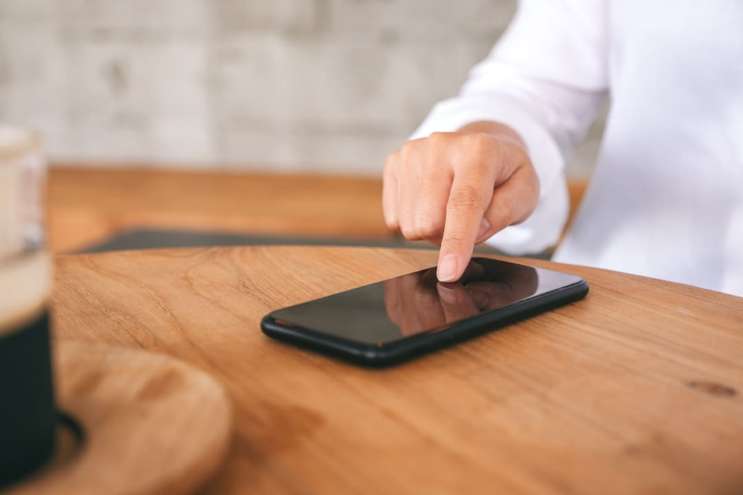 Hand tapping a button on a business website on a smartphone while testing mobile friendliness